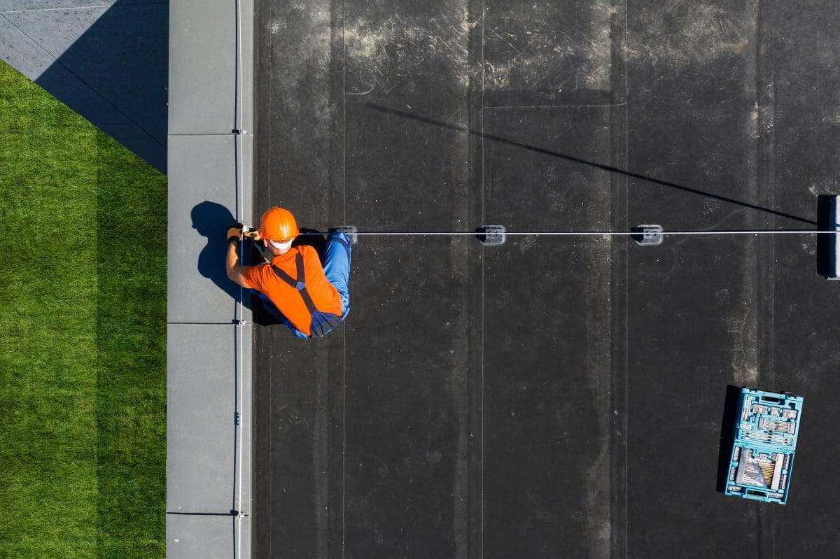 An Overhead view of a roofer installing a lighting rod system on a flat roof