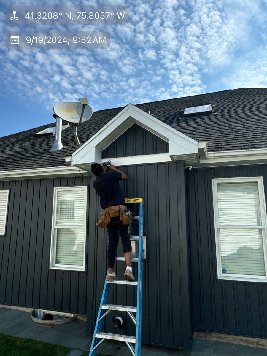 A worker fixing siding on a home.
