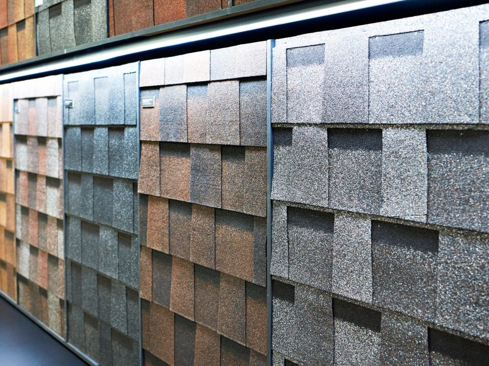 A store display of GAF designer shingles in a variety of brown, gray, and clay-colored shingles.