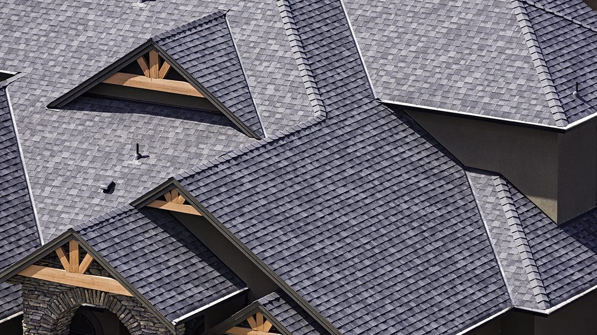 An overhead view of a large house roof made with gray GAF shingles