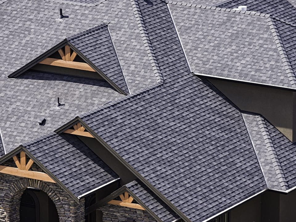 An overhead view of a large house roof made with gray GAF shingles