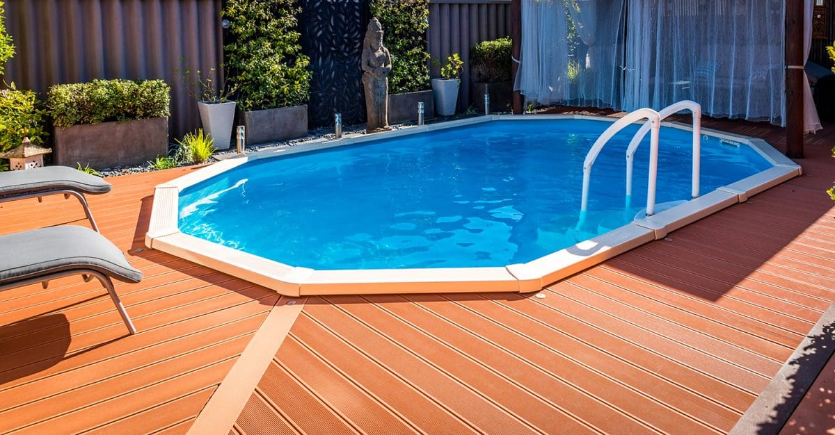 A bright brownish-orange deck surrounding a tiny above-ground pool. Two stunning chairs are to the left of the pool.