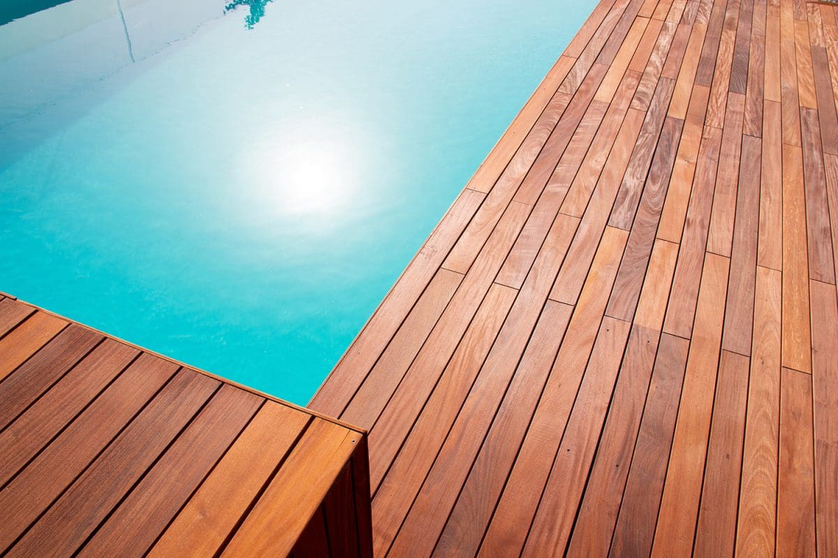 A reddish-brown hardwood deck installed around a pool