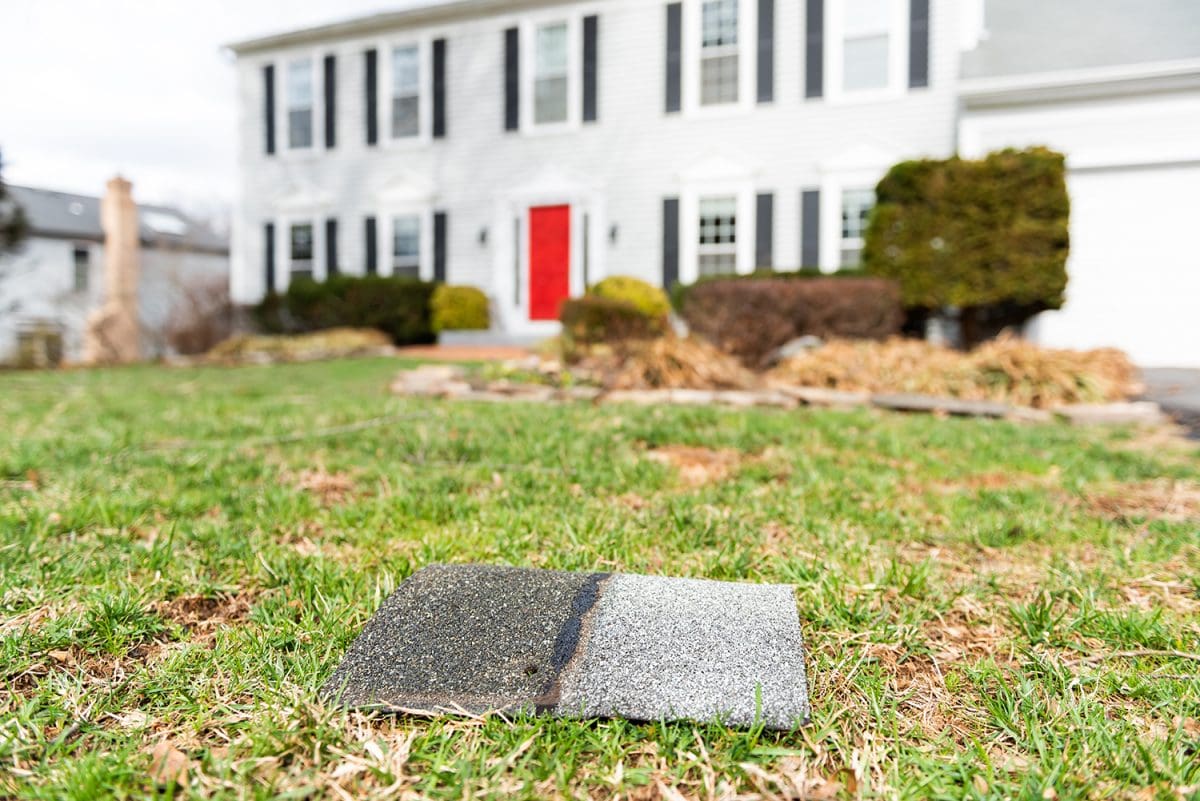 A close-up of a shingle on a front lawn, with a home in the background.