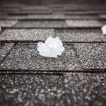 A close-up shot of a roof with hailstones sitting on the shingles