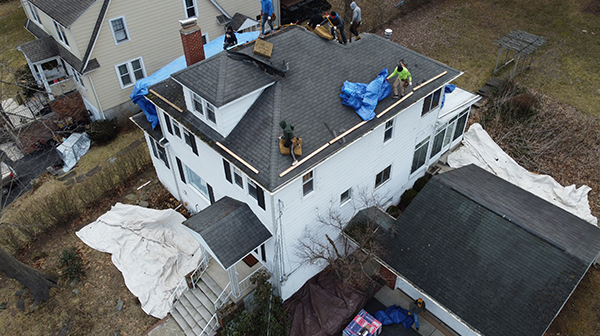 Roofers working on a residential home with storm damage.