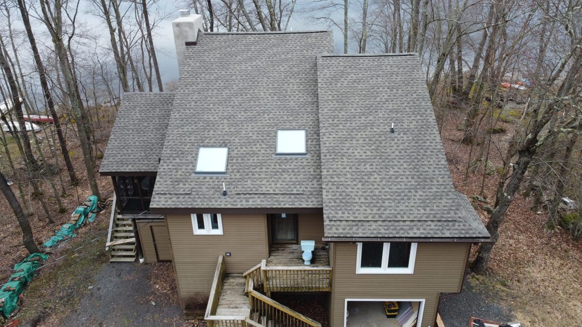 An overhead view of a light grey roof in a wooded area.