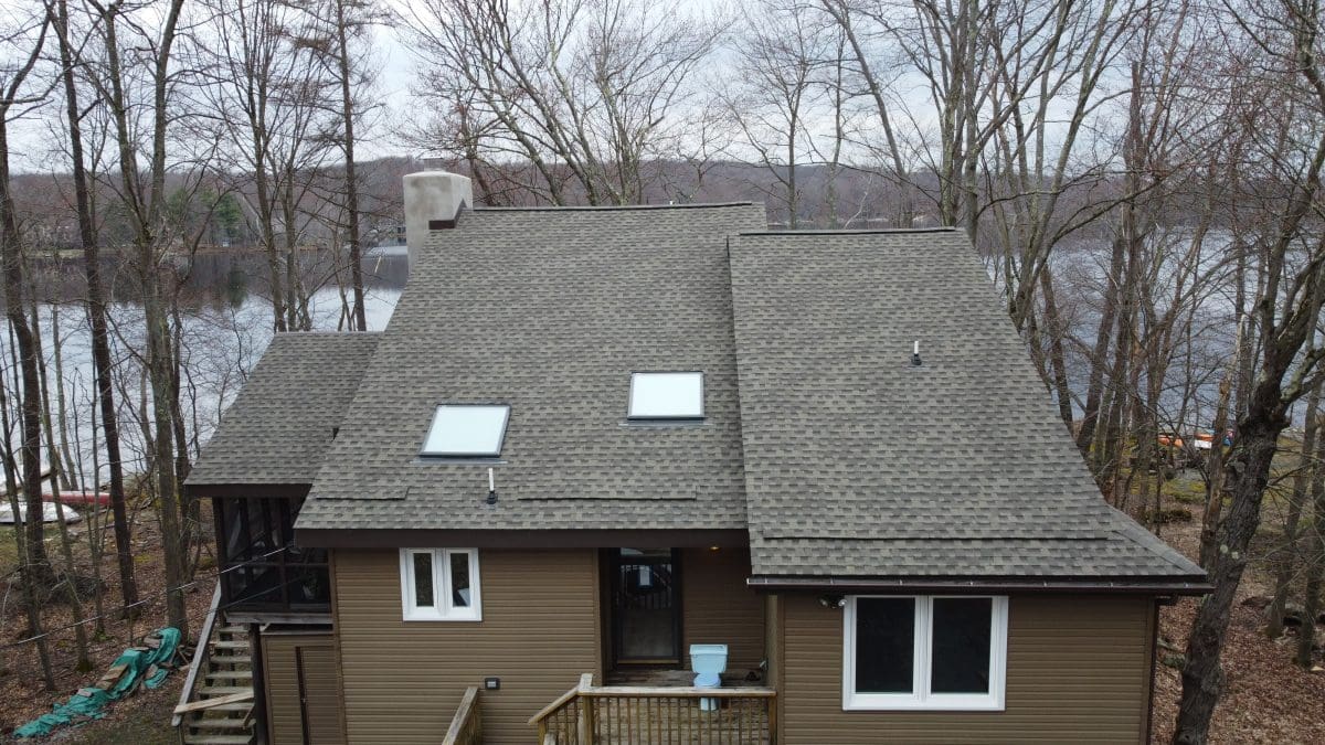 A low-angle view of a steeply slanted brown roof on a river-front home