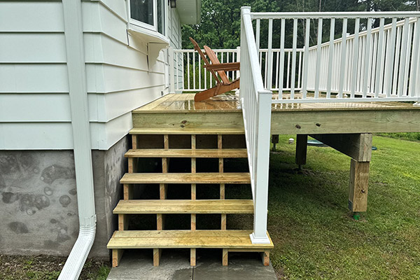 A wood deck installation with white vinyl railing