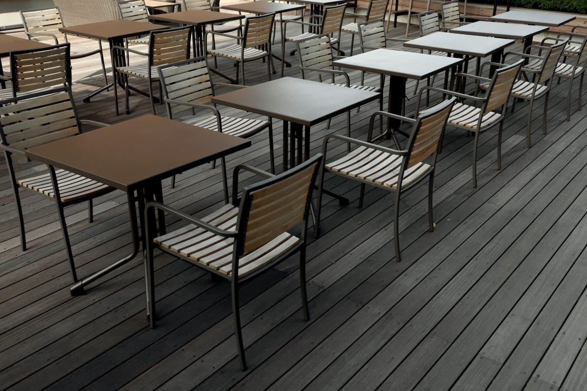 Cafe tables lined up on a wooden deck.