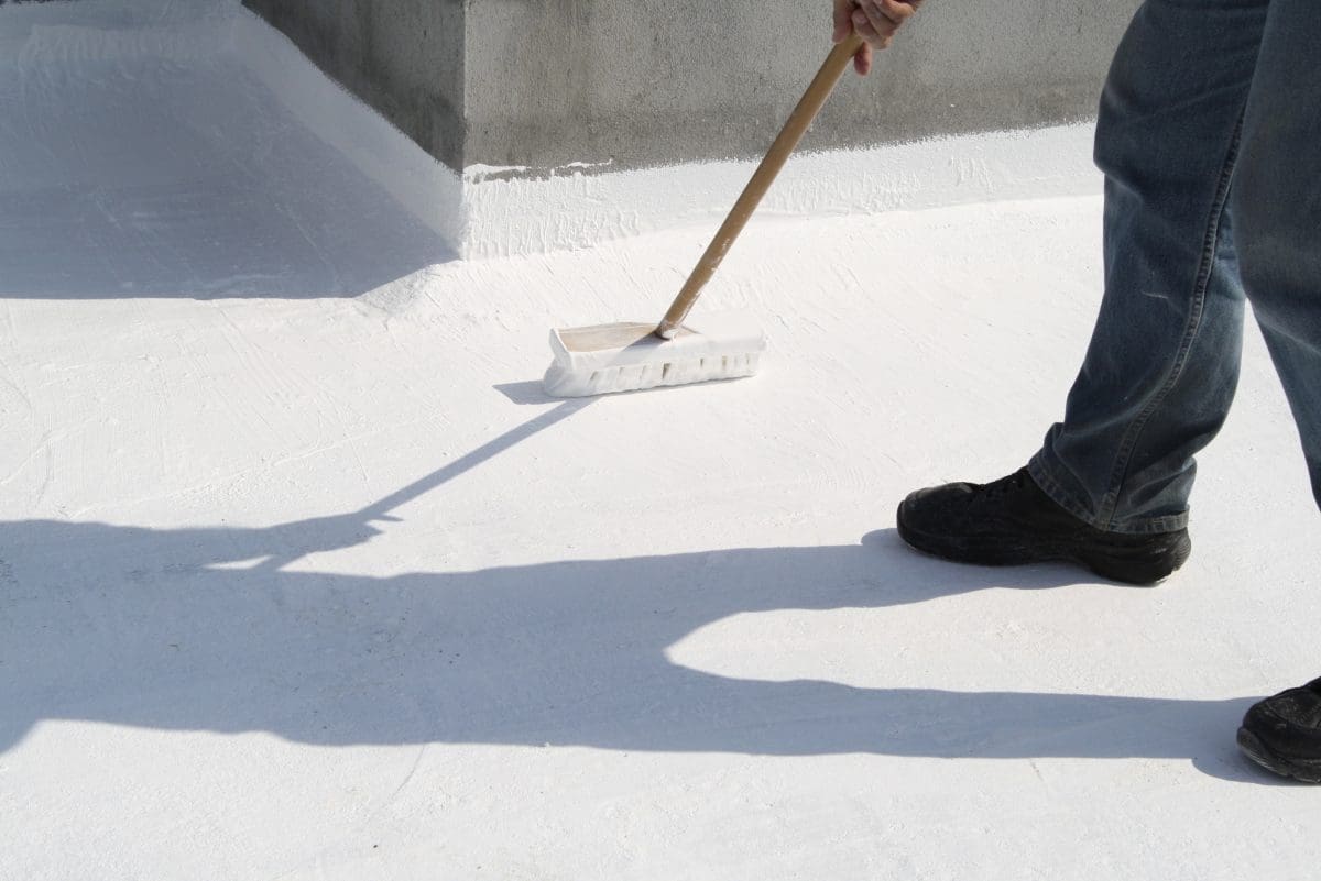 A commercial roofer applies a roof coating to a building.